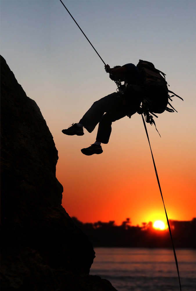 rock climber at sunset time going up a mountain